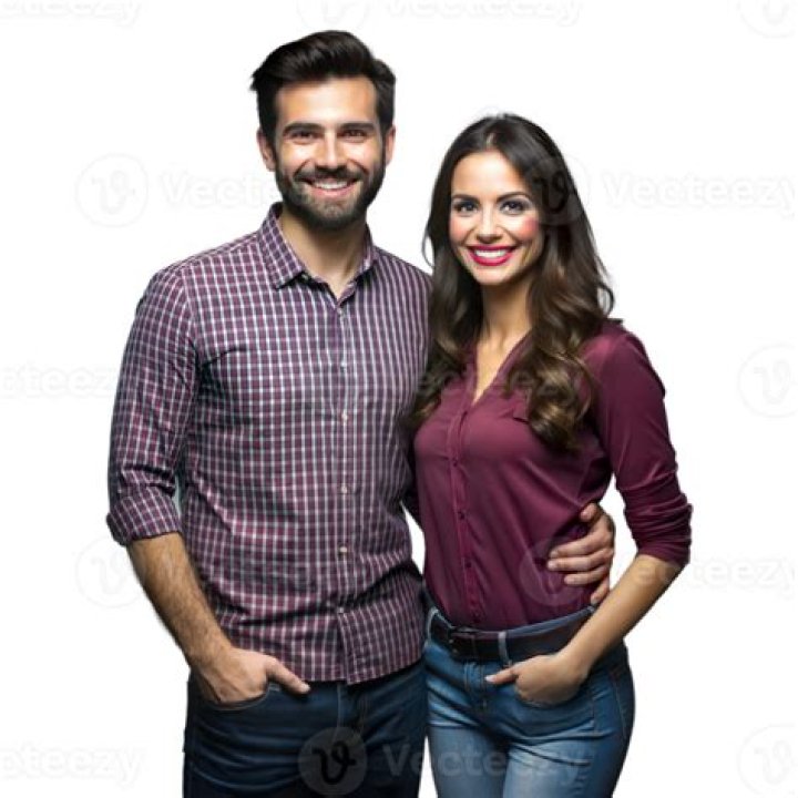 a man and woman standing next to each other in front of a red carpeted wall